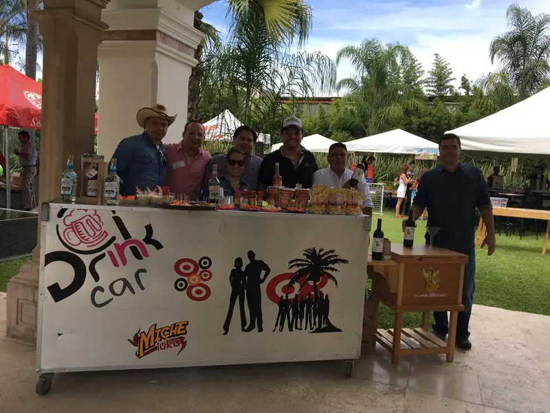 Bartenders de Drink In Car atendiendo una barra en un evento en jardín